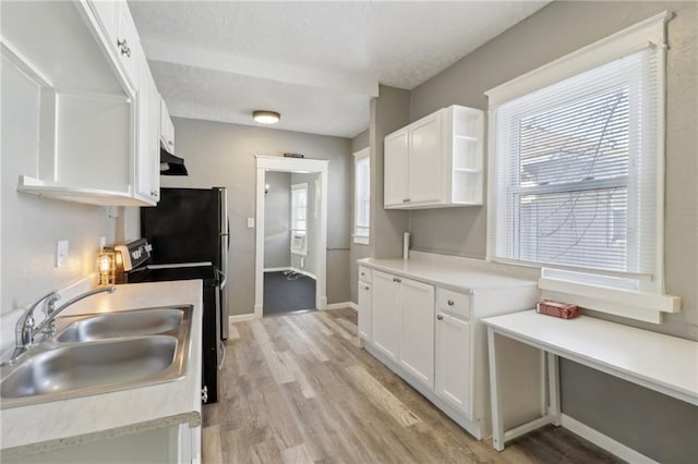 kitchen with a healthy amount of sunlight, white cabinets, electric range, and sink