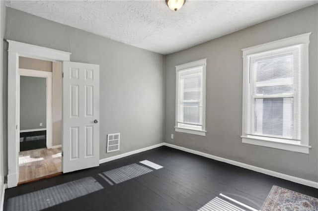 spare room with dark wood-type flooring and a textured ceiling