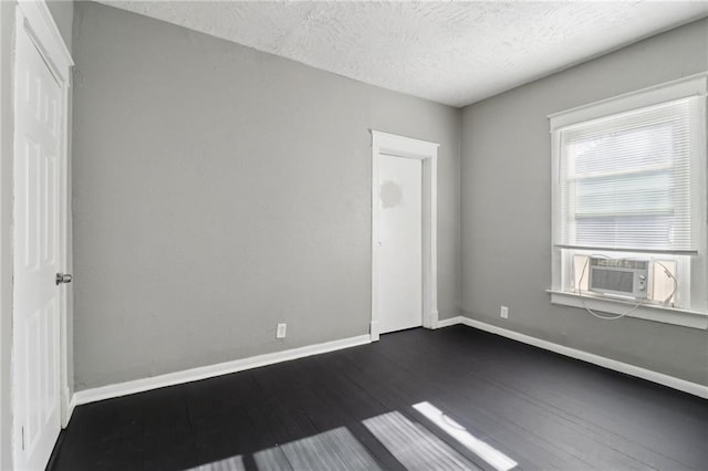 empty room with cooling unit, dark hardwood / wood-style flooring, and a textured ceiling