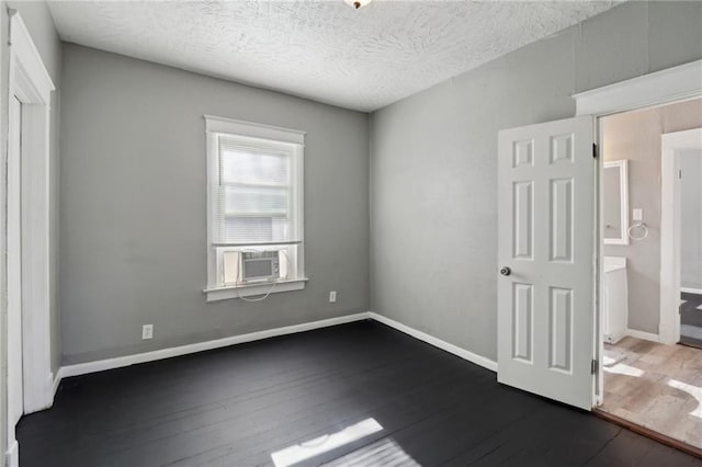 3231 Park Ave, Kansas City, MO 64109 - unfurnished bedroom featuring cooling unit, baseboards, a textured ceiling, and dark wood-style floors