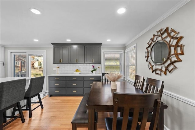 dining area featuring plenty of natural light, light wood-type flooring, and ornamental molding