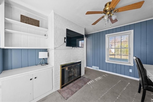 carpeted living room featuring ceiling fan, ornamental molding, and a brick fireplace