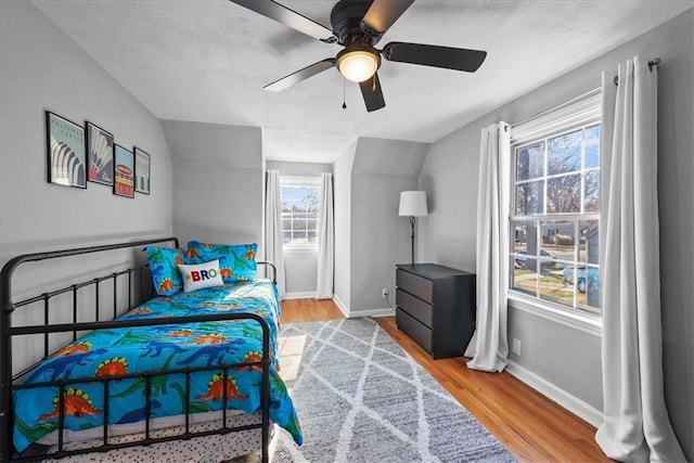 bedroom featuring multiple windows, ceiling fan, wood-type flooring, and vaulted ceiling