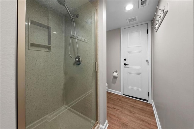 bathroom with hardwood / wood-style floors, an enclosed shower, and toilet