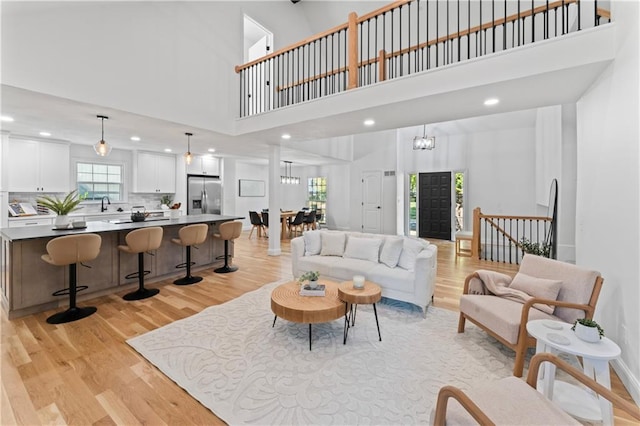 living room with a towering ceiling, light hardwood / wood-style floors, and sink