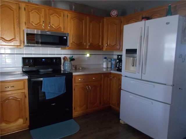 kitchen featuring dark hardwood / wood-style floors, black electric range oven, white refrigerator with ice dispenser, and backsplash