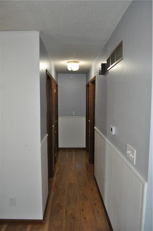 hall featuring a textured ceiling and dark wood-type flooring