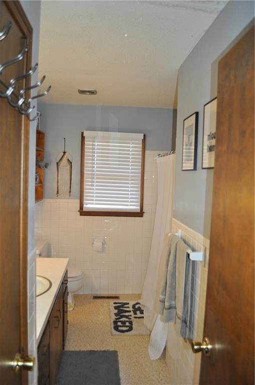 bathroom featuring a shower with curtain, vanity, toilet, and tile walls