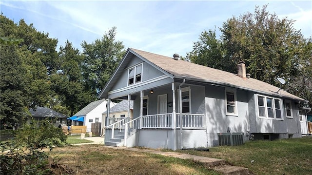 view of front of property featuring central AC unit, covered porch, and a front yard