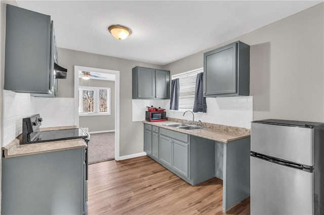 kitchen with gray cabinetry, sink, ceiling fan, stainless steel fridge, and light hardwood / wood-style floors