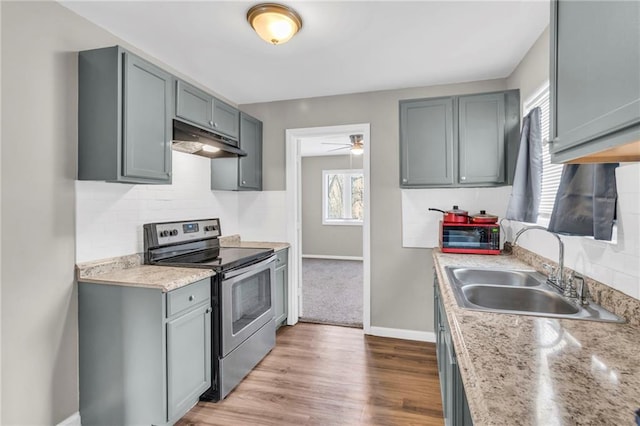 kitchen with stainless steel electric stove, gray cabinets, sink, and light hardwood / wood-style flooring