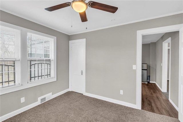 carpeted empty room with ceiling fan and crown molding