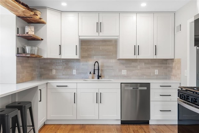 kitchen featuring backsplash, stainless steel appliances, sink, light hardwood / wood-style flooring, and white cabinets