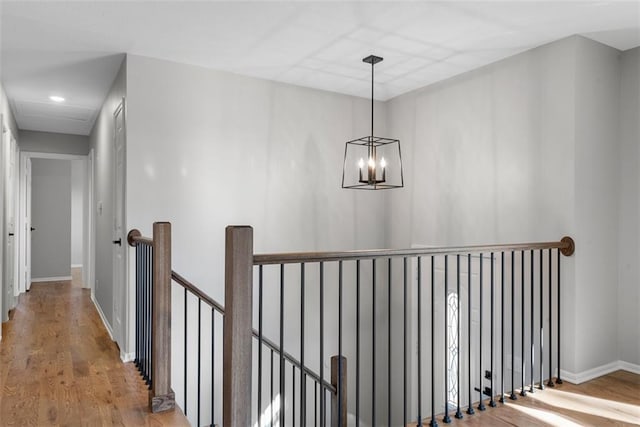 corridor featuring light wood-type flooring and a notable chandelier