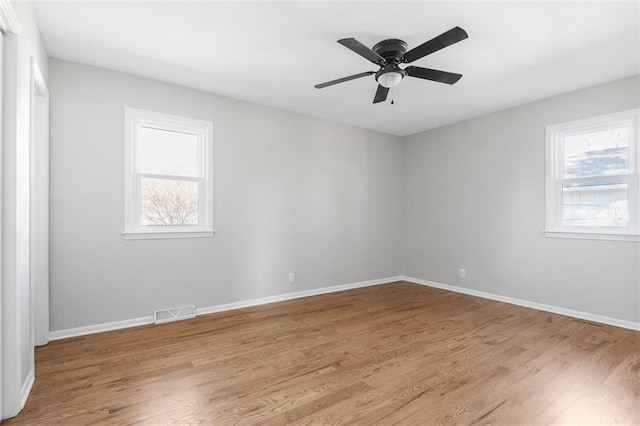 spare room featuring light wood-type flooring, ceiling fan, and a healthy amount of sunlight