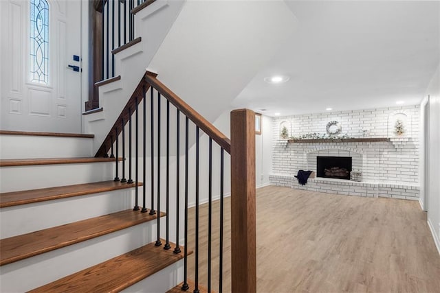 stairway with hardwood / wood-style flooring, a fireplace, and brick wall