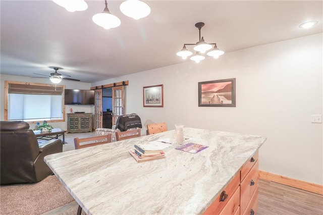 dining room with ceiling fan with notable chandelier and light hardwood / wood-style flooring