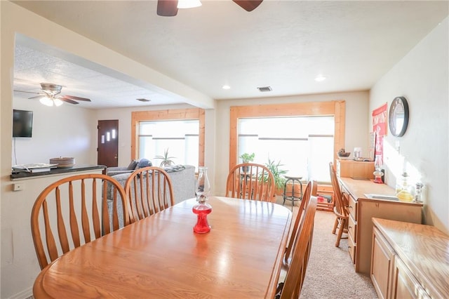 carpeted dining area with ceiling fan