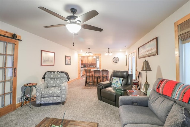 living room featuring carpet floors, ceiling fan, and a barn door