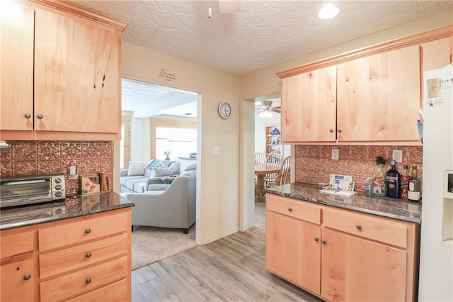 kitchen with white fridge, light brown cabinets, dark stone countertops, and light hardwood / wood-style flooring