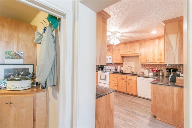 kitchen with white appliances, dark stone counters, sink, light wood-type flooring, and light brown cabinetry