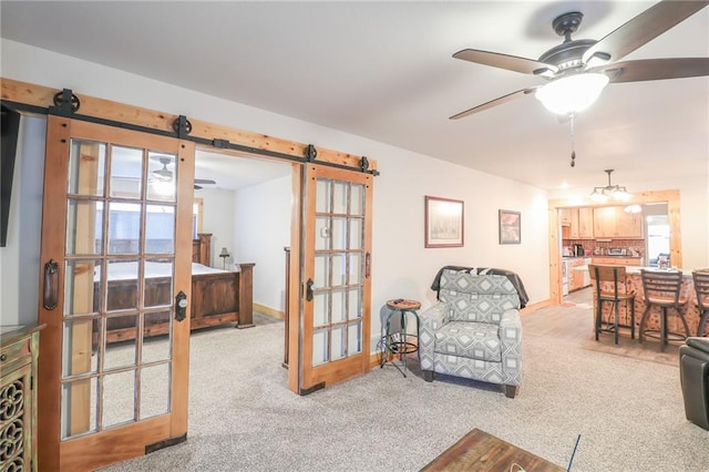 living room featuring light carpet, a barn door, and ceiling fan