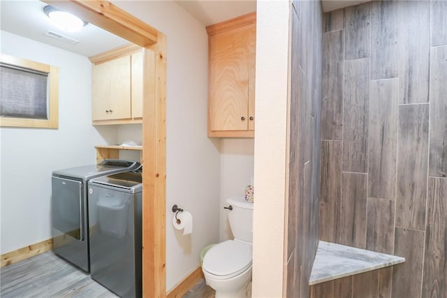 bathroom featuring washing machine and clothes dryer, hardwood / wood-style floors, walk in shower, and toilet