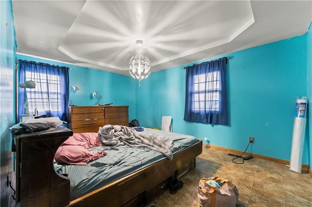 bedroom featuring a chandelier, multiple windows, a raised ceiling, and baseboards