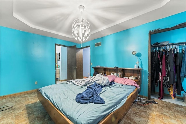 bedroom with baseboards, a tray ceiling, a closet, and a notable chandelier