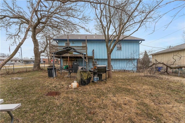 rear view of property featuring stairway, fence, and a lawn