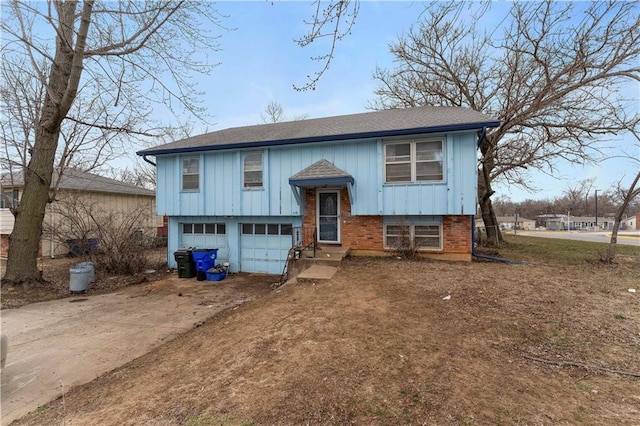 raised ranch featuring a garage, concrete driveway, brick siding, and board and batten siding