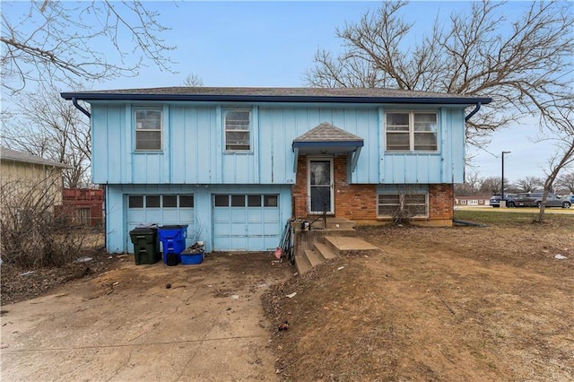 split foyer home with a garage, concrete driveway, brick siding, and board and batten siding