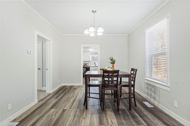 dining area featuring dark hardwood / wood-style flooring, ornamental molding, sink, and an inviting chandelier