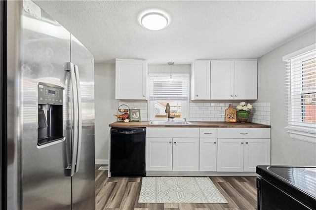 kitchen with butcher block counters, white cabinetry, sink, and black appliances