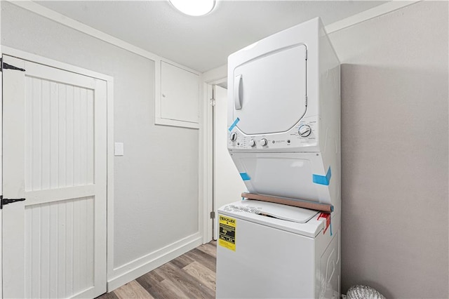 laundry area featuring stacked washer and dryer and light hardwood / wood-style floors