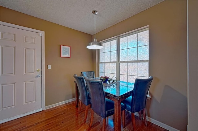 dining space featuring a textured ceiling and hardwood / wood-style floors