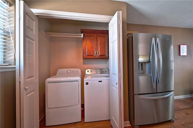 washroom featuring light wood-type flooring, washer and dryer, and a textured ceiling