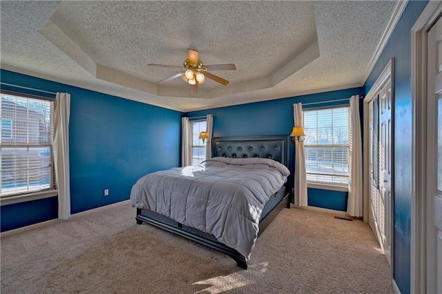 carpeted bedroom featuring ceiling fan, a raised ceiling, and multiple windows