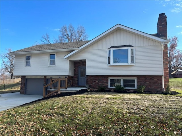 raised ranch with a garage, brick siding, driveway, a front lawn, and a chimney