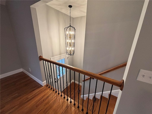 stairs featuring a chandelier, wood finished floors, and baseboards