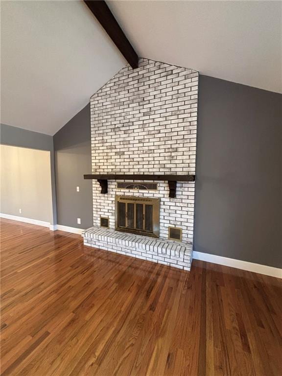 unfurnished living room featuring a fireplace, lofted ceiling with beams, baseboards, and wood finished floors