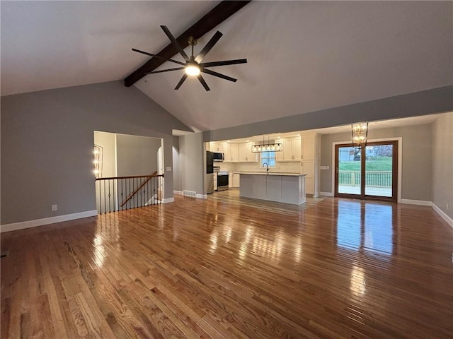 unfurnished living room with beam ceiling, hardwood / wood-style flooring, a sink, baseboards, and ceiling fan with notable chandelier