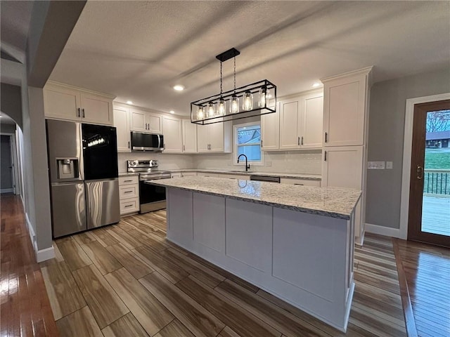 kitchen with arched walkways, stainless steel appliances, a sink, and dark wood finished floors