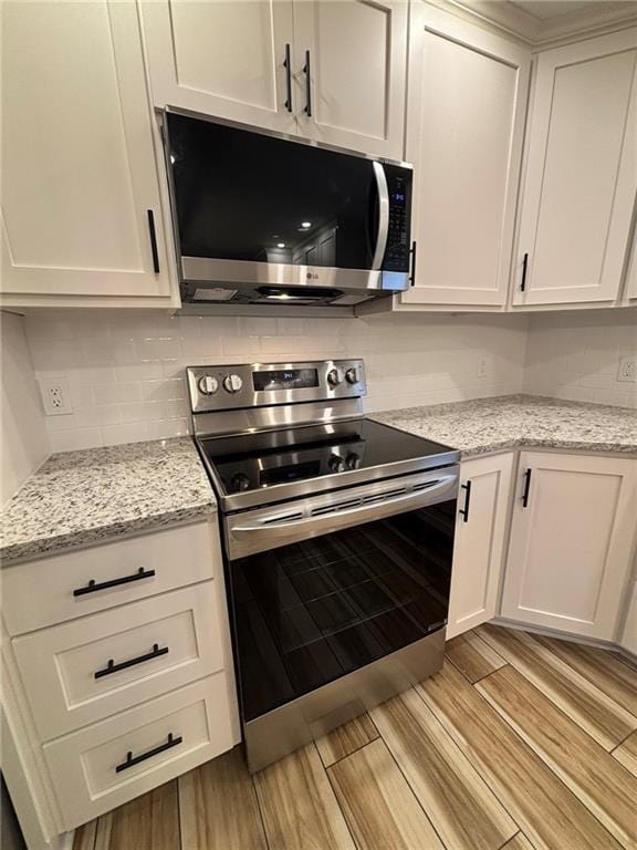 kitchen featuring white cabinets, appliances with stainless steel finishes, decorative backsplash, and wood finish floors