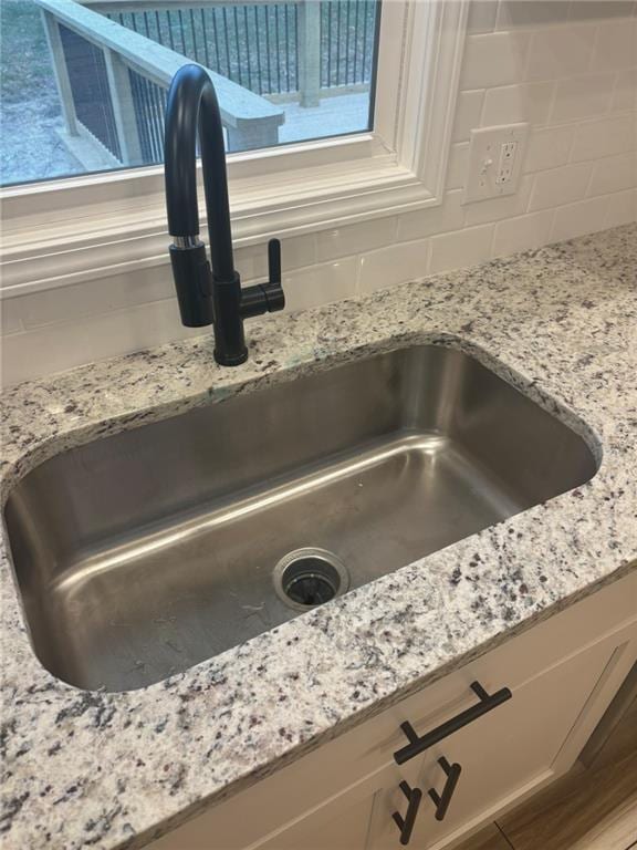 details with tasteful backsplash, a sink, and light stone countertops