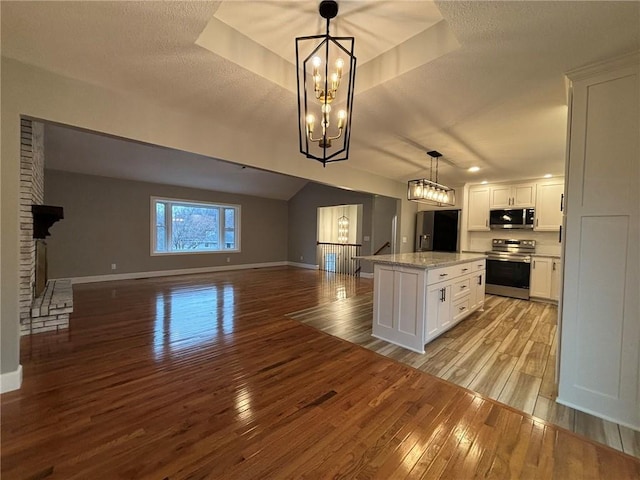 kitchen with light wood-type flooring, white cabinets, stainless steel appliances, and open floor plan