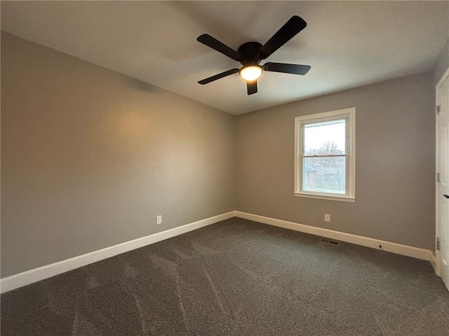 empty room with ceiling fan, dark carpet, visible vents, and baseboards