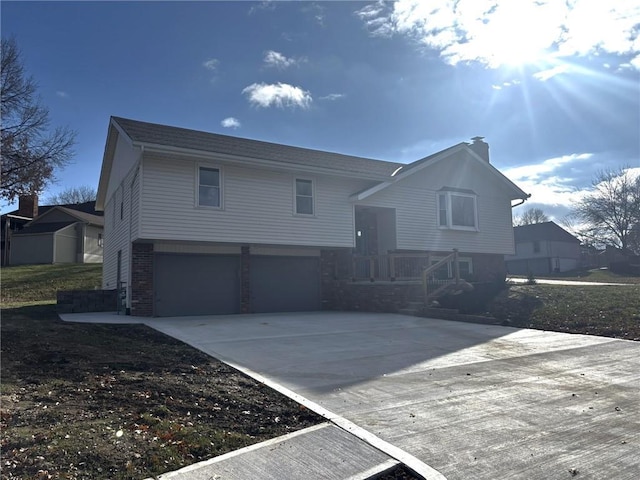 view of front facade with driveway, a garage, a chimney, and brick siding