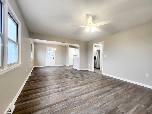 spare room featuring ceiling fan with notable chandelier and dark wood-type flooring