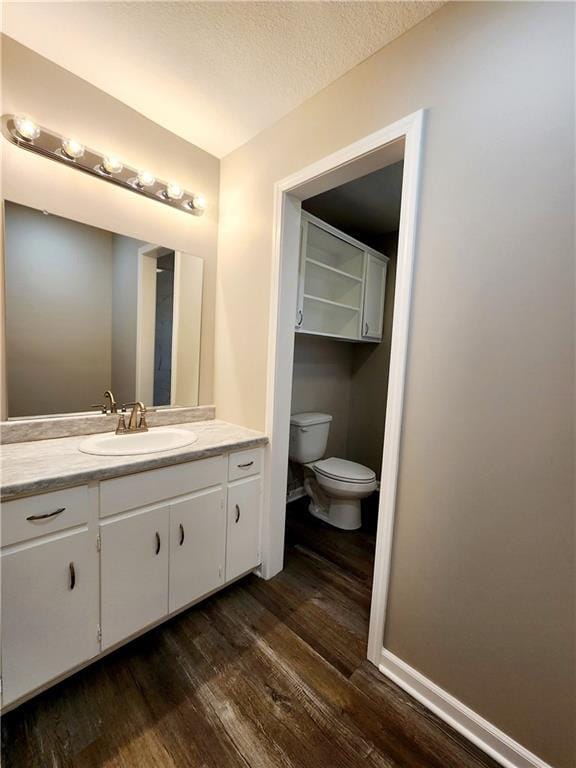 bathroom with vanity, wood-type flooring, a textured ceiling, and toilet